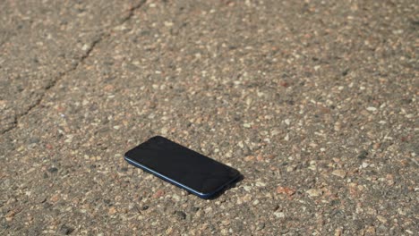 close-up: vehicle tire runs over smartphone lying on street pavement