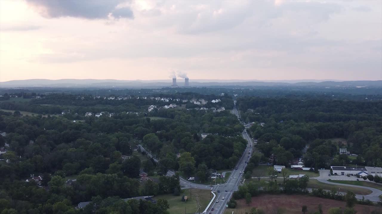 Sun setting over housing development power plant in background
