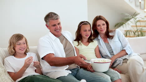 family eating popcorn while watching the television
