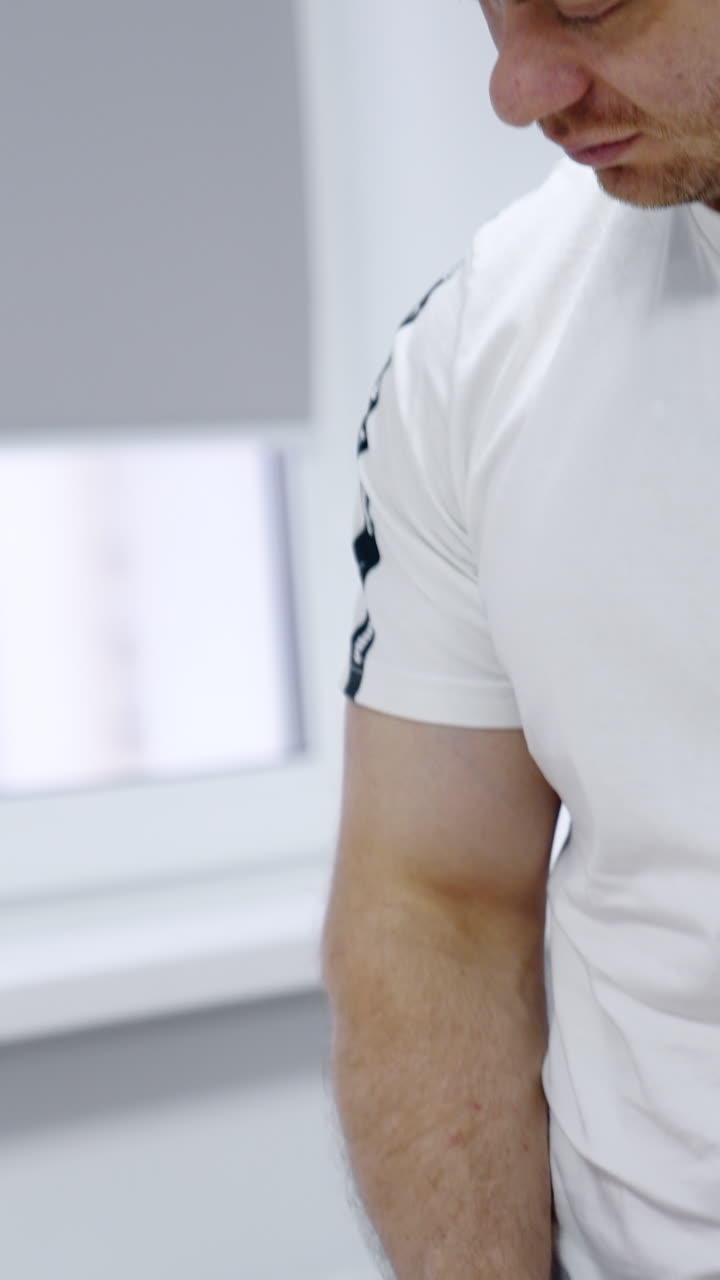 Man holding his wife's hand. Woman lies in a hospital bed going through the contractions. Vertical video