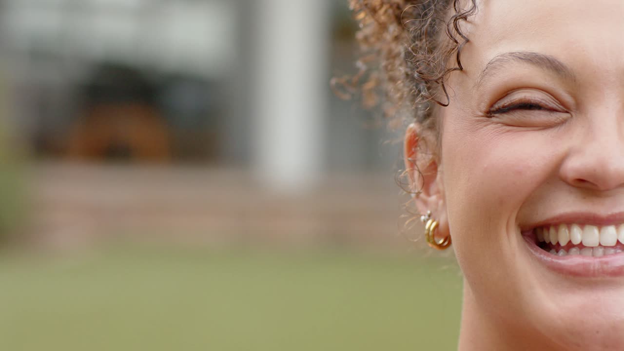 Donna afroamericana che sente una voce fuori campo, trasformando il sorriso in una risata sul prato, con orecchini a cerchio d'oro.
