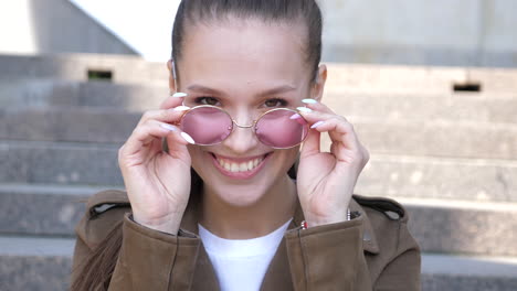 woman laughing on stairs with pink sunglasses