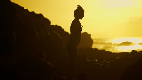woman in silhouette yoga pose at sunset beach