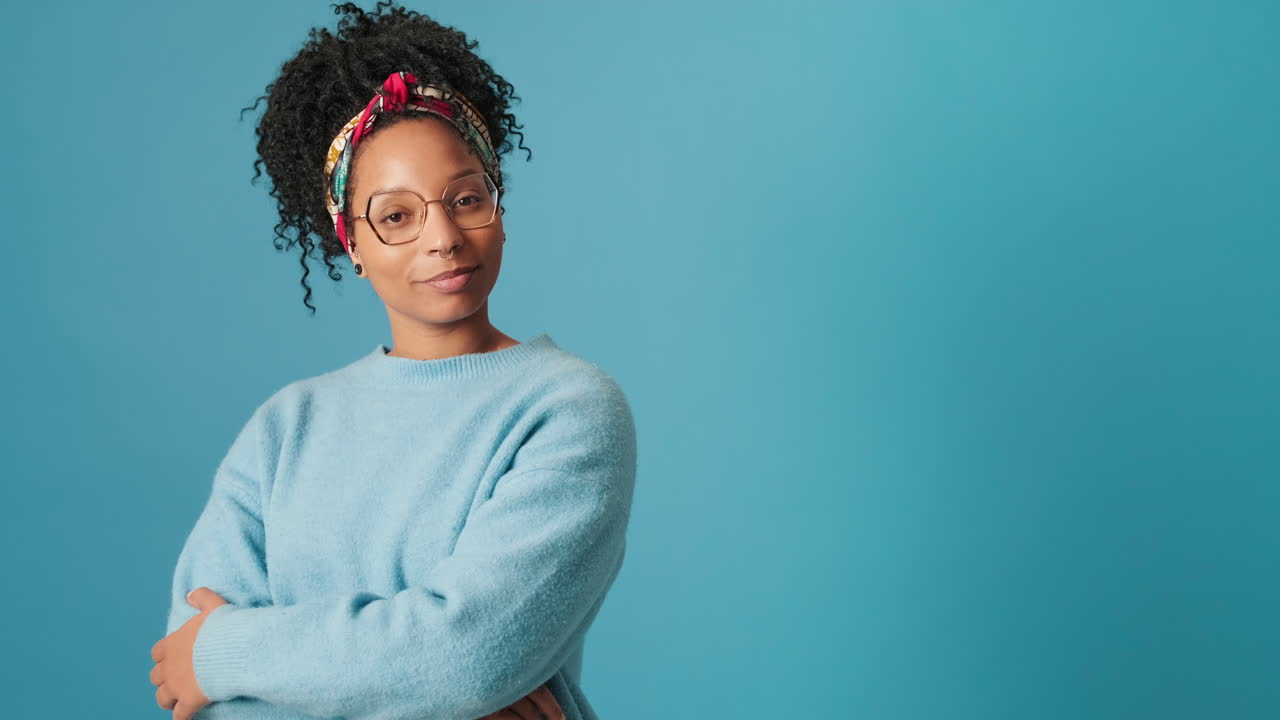 Confident Young Woman with Curly Hair and Glasses Smiling at Camera