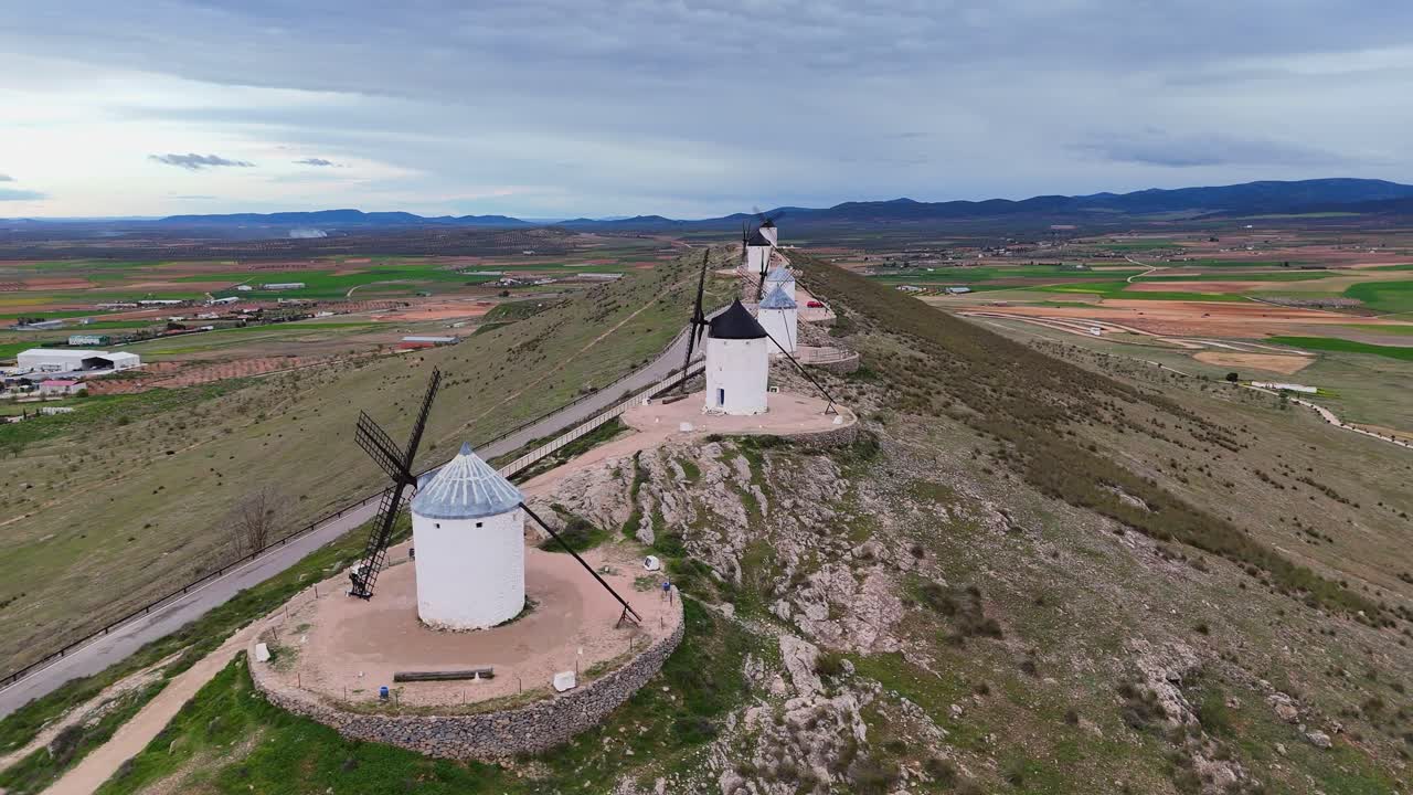Slowmotion video of Consuegra windmills with agricultural fields in background