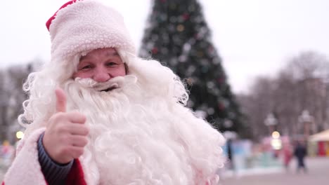 santa claus shows his thumb up looks at the camera and smiles santa claus shows his thumb up looks at the camera and smiles smiling santa shows thumb up christmas concept