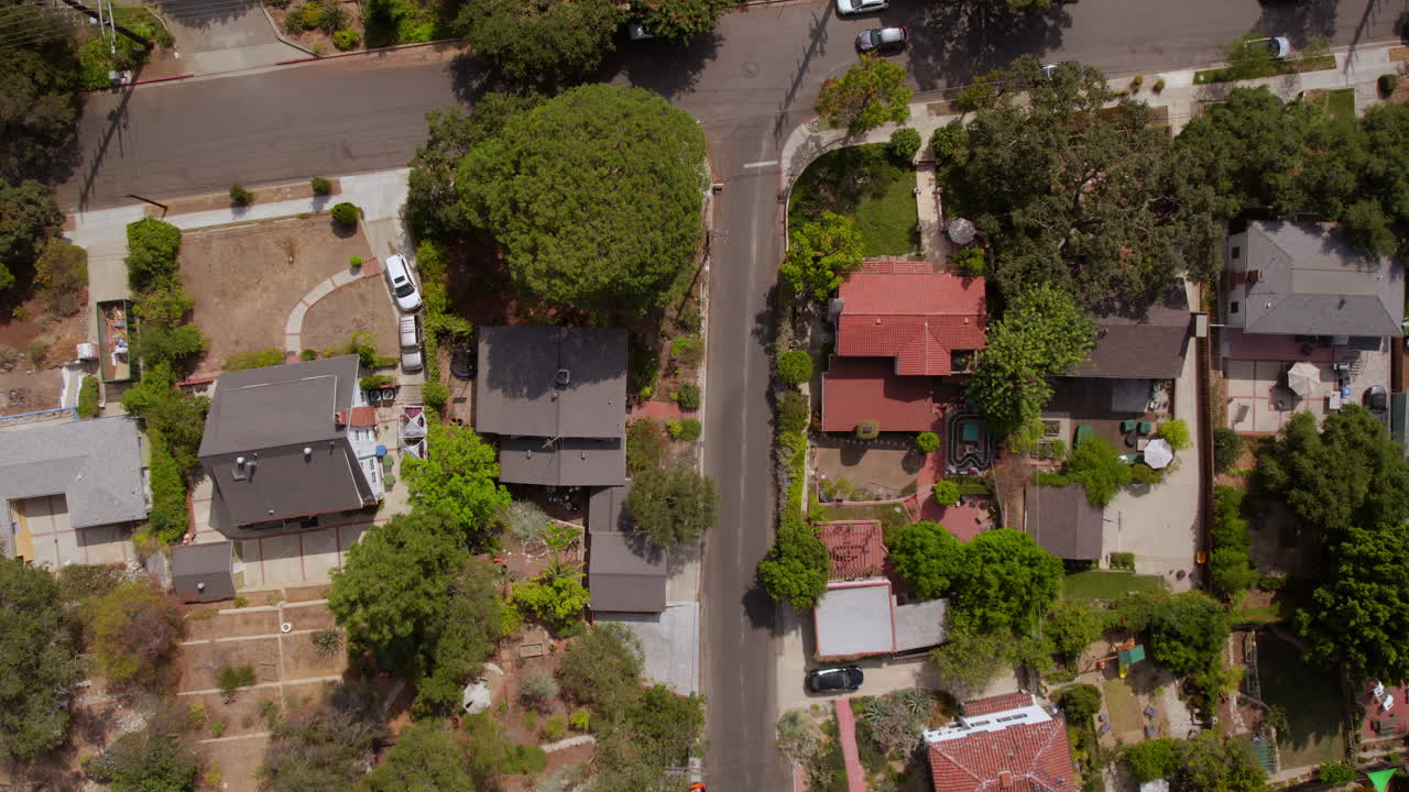 vista aérea de casas y calles en el barrio de eagle rock en los ángeles, california, con desplazamiento hacia arriba para revelar un automóvil que se detiene en un lugar de estacionamiento en un estacionamiento