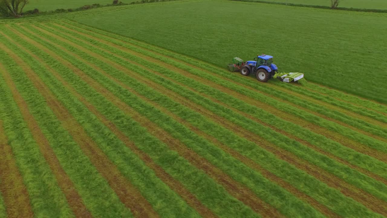 Veduta aerea di un trattore che taglia l'erba in un grande campo verde