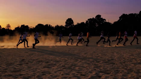 group of runners kicking up dust at sunset