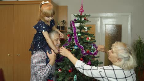 Niña-Con-Familia-De-Abuelos-Mayores-Decorando-árbol-De-Navidad-Artificial,-Vacaciones-De-Año-Nuevo