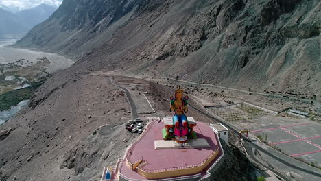 aerial-shot-of-camera-slowly-flying-towards-a-tall-budha-statue-at-diskit-gompa,-ladakh