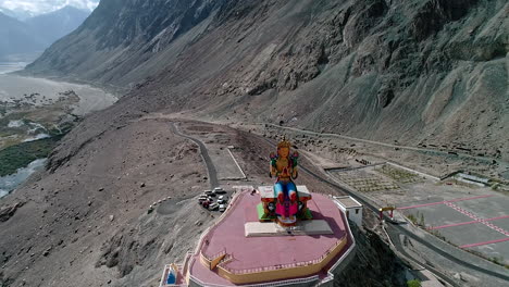 aerial shot of camera slowly flying towards a tall budha statue at diskit gompa, ladakh