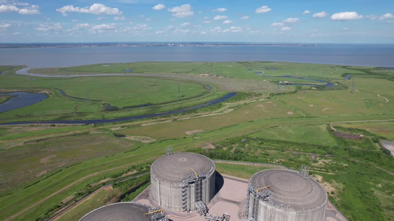 Open countryside pull back reveal of National grid Grain LNG Terminal gas storage Kent UK drone aerial view