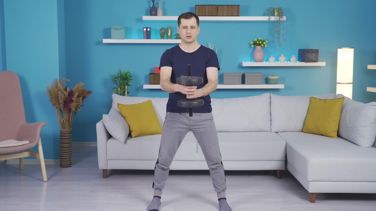 성숙한 남자가 집에서 덤벨로 운동을 하고 있습니다.