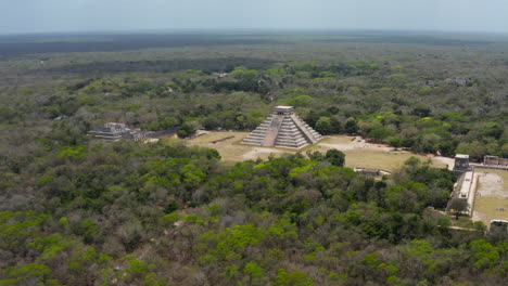 Aerial-footage-of-Temple-of-Kukulcan---El-Castillo.-Tourist-attraction-inside-Yucatan-rain-forest.-Historical-monuments-of-pre-Columbian-era,-Chichen-Itza,-Mexico.