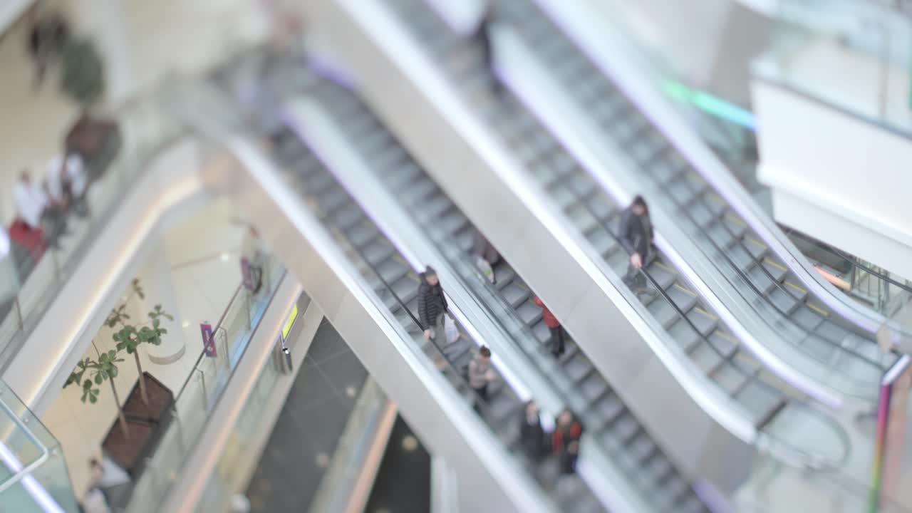 People in motion in escalators at the modern shopping mall. Tilt shift lens shooting with super shallow depth of field.