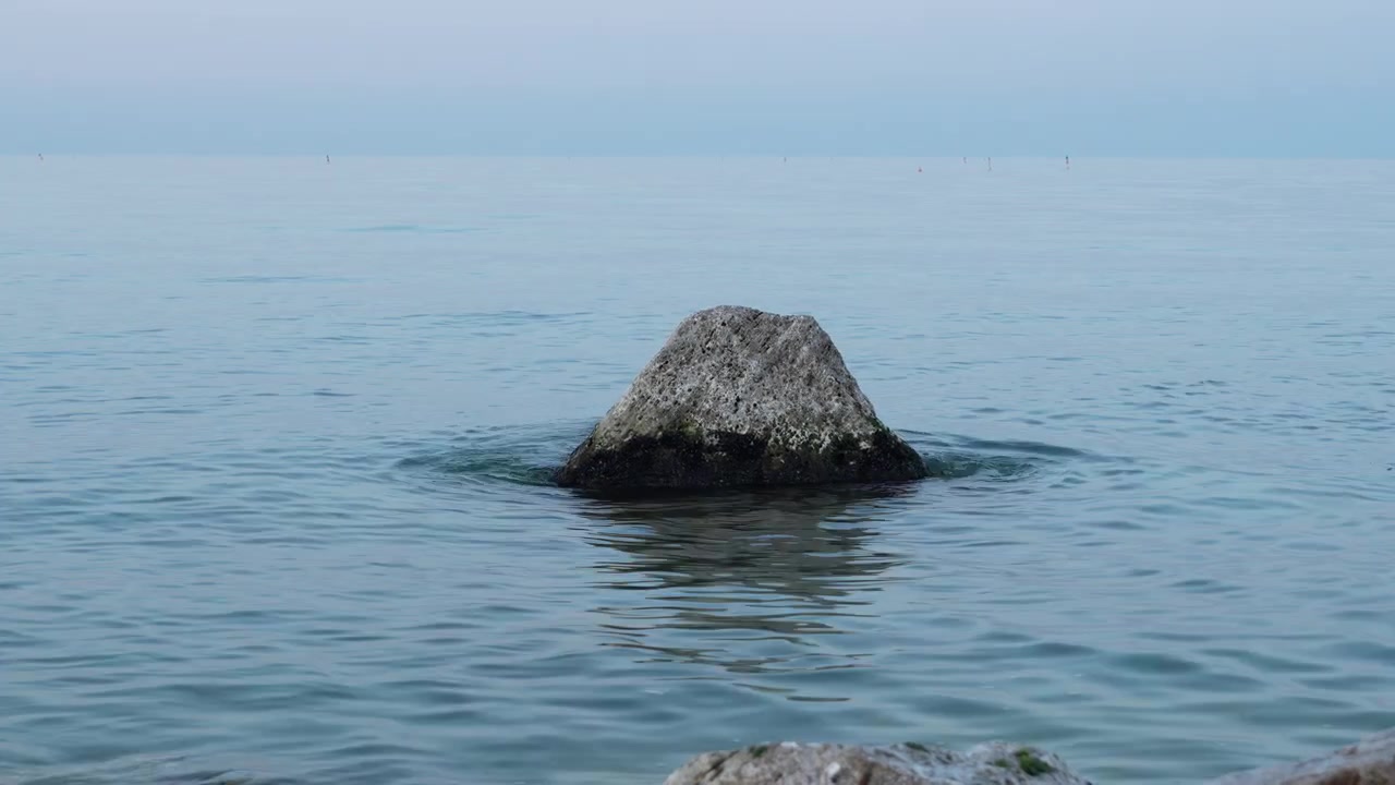 Una bellissima roccia singola isolata che si erge solitaria nelle calme acque blu del Mare Adriatico vicino alla costa di Porto Recanati in Italia.