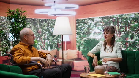 Mature-man-wheelchair-user-and-woman-laughing-and-chatting-at-home