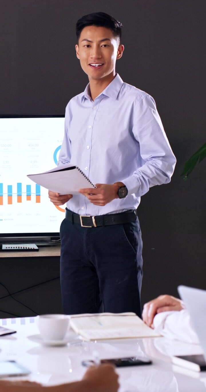Giovane imprenditore asiatico che presenta dati ai colleghi in ufficio