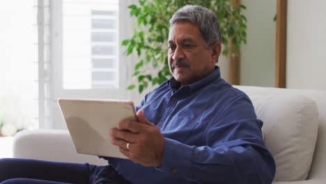 Senior-mixed-race-man-using-tablet-in-living-room