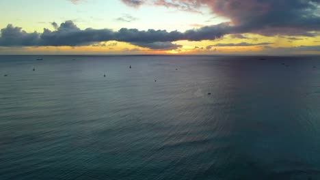 Vista-Aérea-De-Una-Flota-De-Veleros-Esparcidos-Por-El-Océano-Frente-A-La-Costa-De-La-Playa-De-Waikiki-En-Honolulu,-Hawaii-Al-Atardecer