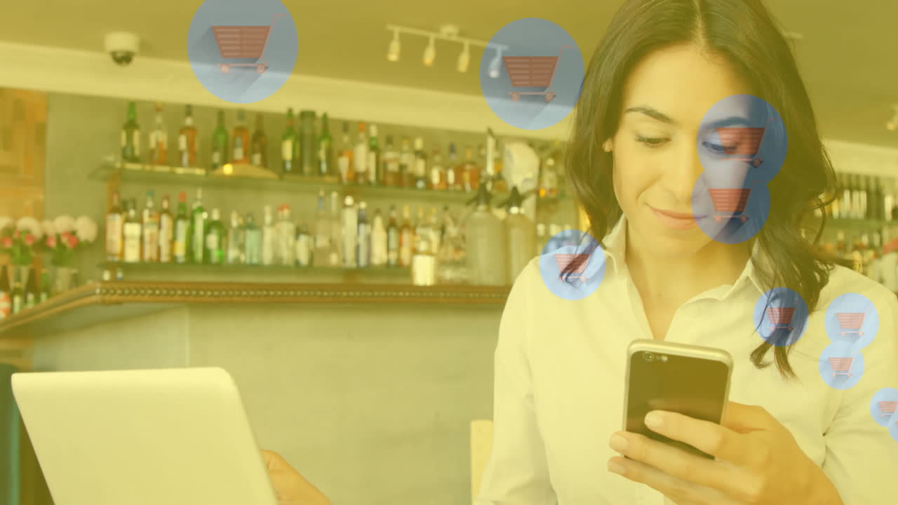 Using smartphone and laptop, woman seeing shopping cart animation in cafe