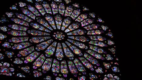 a round stained glass window in a darkened cathedral