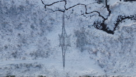 electrical power tower in a winter outdoor landscape, aerial top down