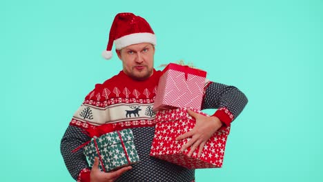 lovely man in christmas red sweater hat presenting christmas gift boxes stretches out hand to camera