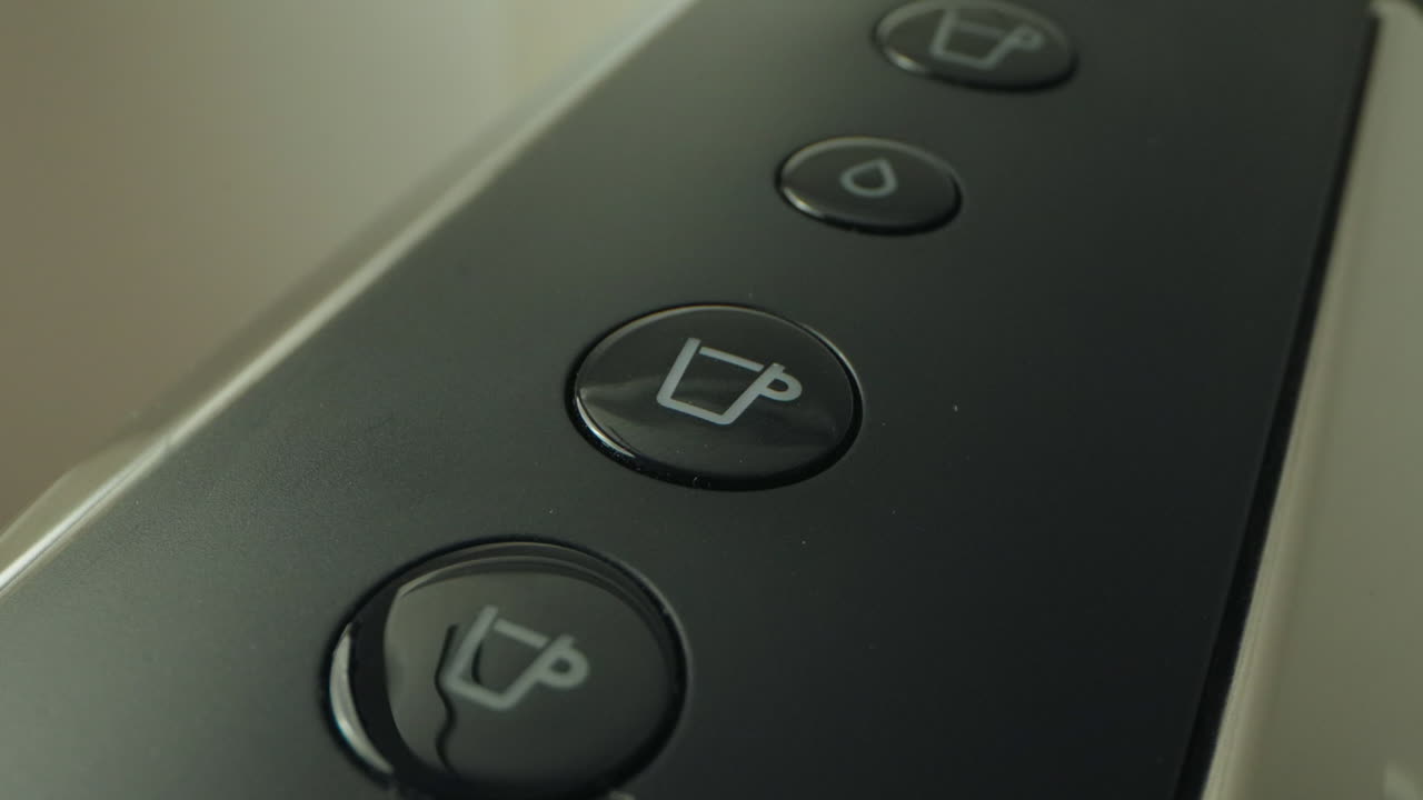 A finger presses a button on a coffee machine to select a drink option