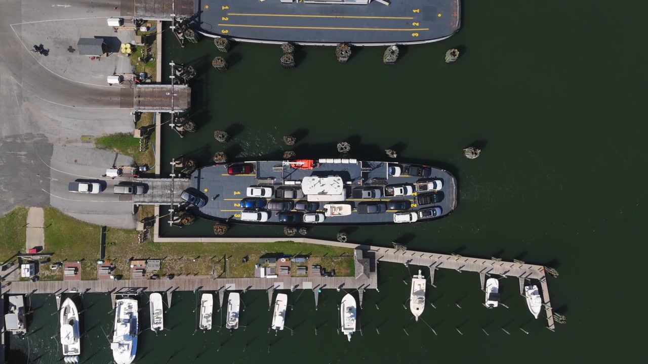 Hatteras færgeterminal på Hatteras Island i Outer Banks i North Carolina, USA, med køretøjer, der kører ombord på en færge - set fra luften med drone