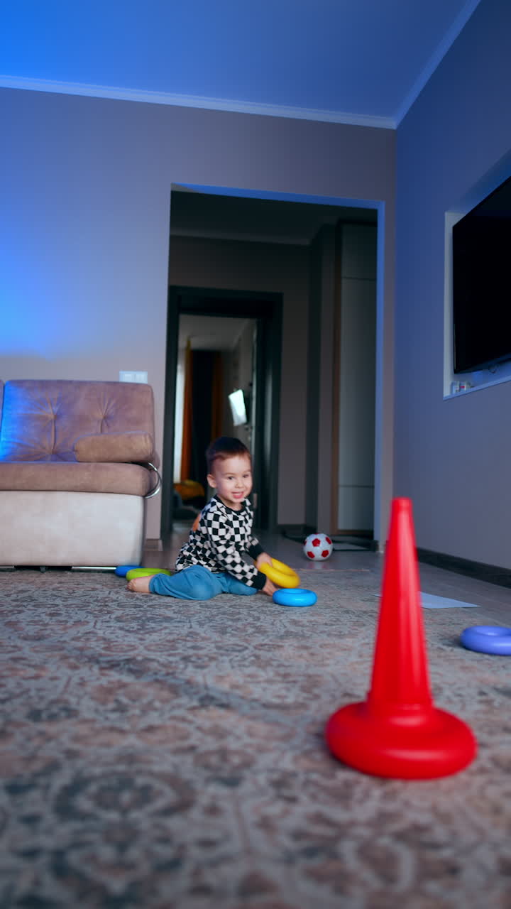 Energetic baby boy throwing the toys cheerfully at home. Kid tosses a ring from the pyramid to the basis. Vertical video.