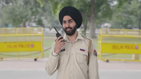 happy sikh indian police man talking on radio