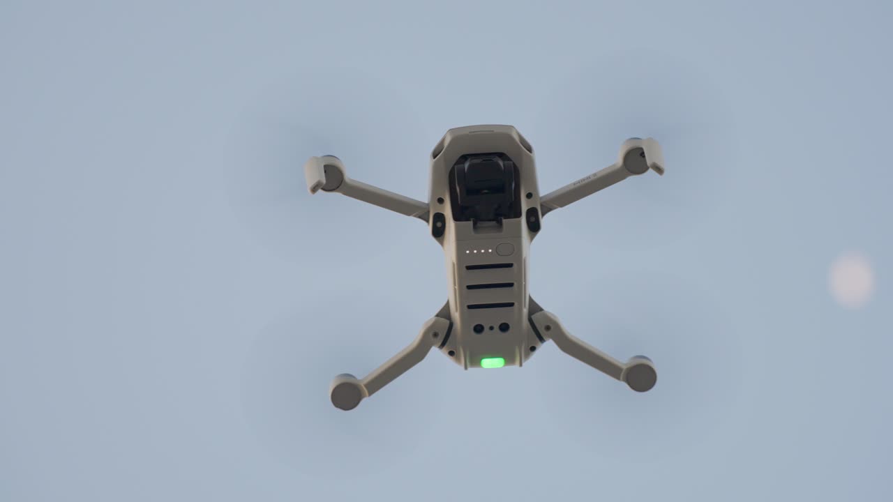 Drone flying high in the sky during daytime, showing its underside
