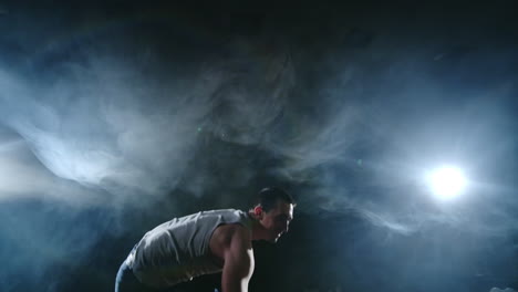 male dancer performs a stunt jump with a rotation back and a revolution in the scene in the smoke in the spotlight. modern ballet