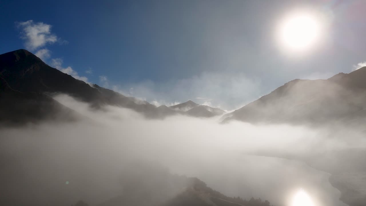 Drone captures misty mountains in Queenstown, New Zealand, during a crisp winter sunrise with clear skies and vibrant lighting