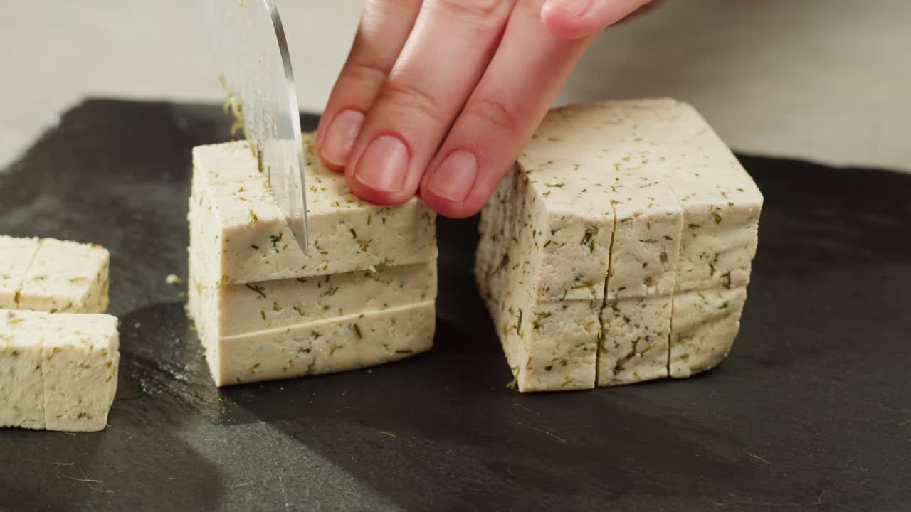 Fried tofu with sesame seeds and spices on cast iron pan, cooking japanese salad. Healthy ingredient for cooking vegan vegetarian diet food. Roasted tofu over black background.