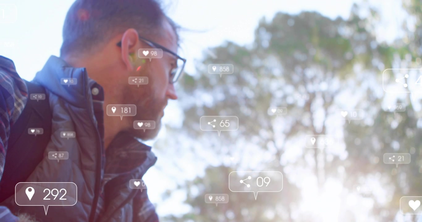 Mature man tapping smartphone in sunlit park, generating social notifications while scanning trees