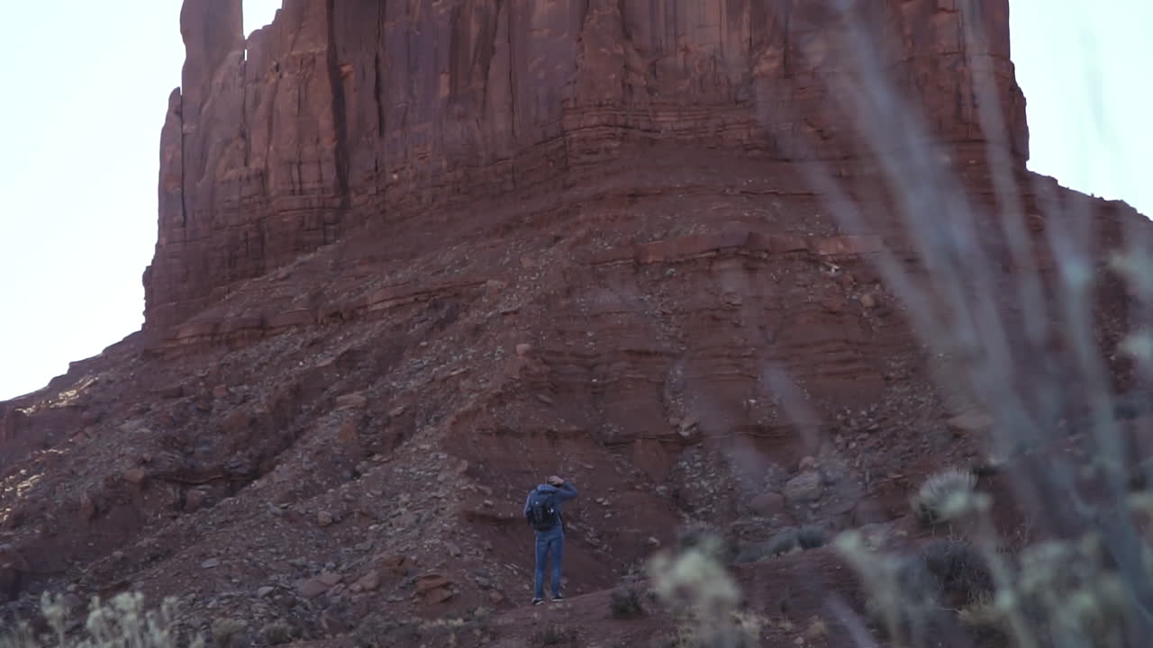 excursionista admirando la formación de roca roja mitten en monument valley arizona