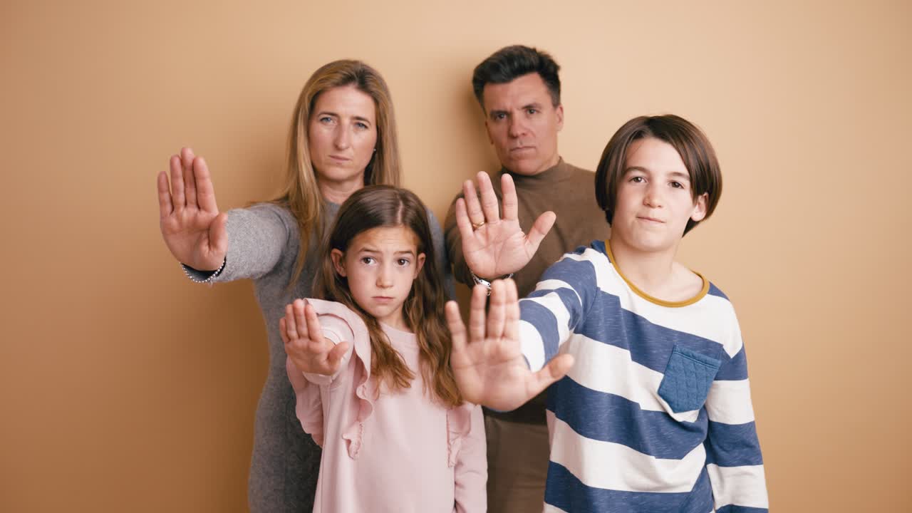 Familie laver stoptegn med hænderne mod beige baggrund