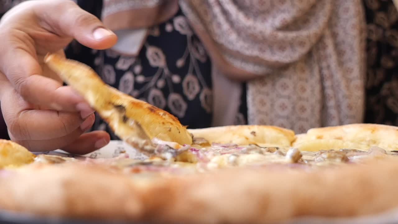 Close-up of person taking a slice of pizza