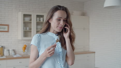 una joven mujer de negocios hablando por teléfono móvil en el interior de la cocina.
