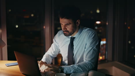 unhappy manager sitting dark office looking laptop close up. sad analyst working