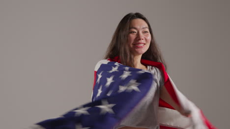 Fotografía-De-Estudio-De-Cabeza-Y-Hombros-De-Una-Mujer-Envuelta-En-La-Bandera-Estadounidense-Celebrando-El-4-De-Julio,-Día-De-La-Independencia