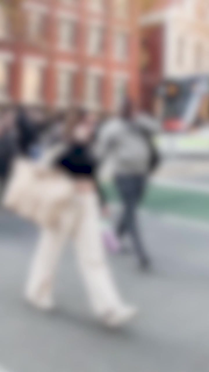 Blurred motion of diverse people walking across an urban intersection during a bright day.