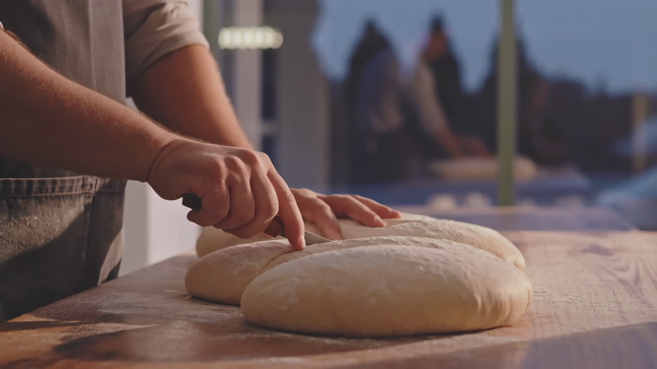Baker's hands cutting dough for bread preparation