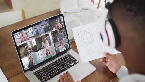 African-american-male-college-student-holding-notes-while-having-a-video-call-on-laptop-at-home