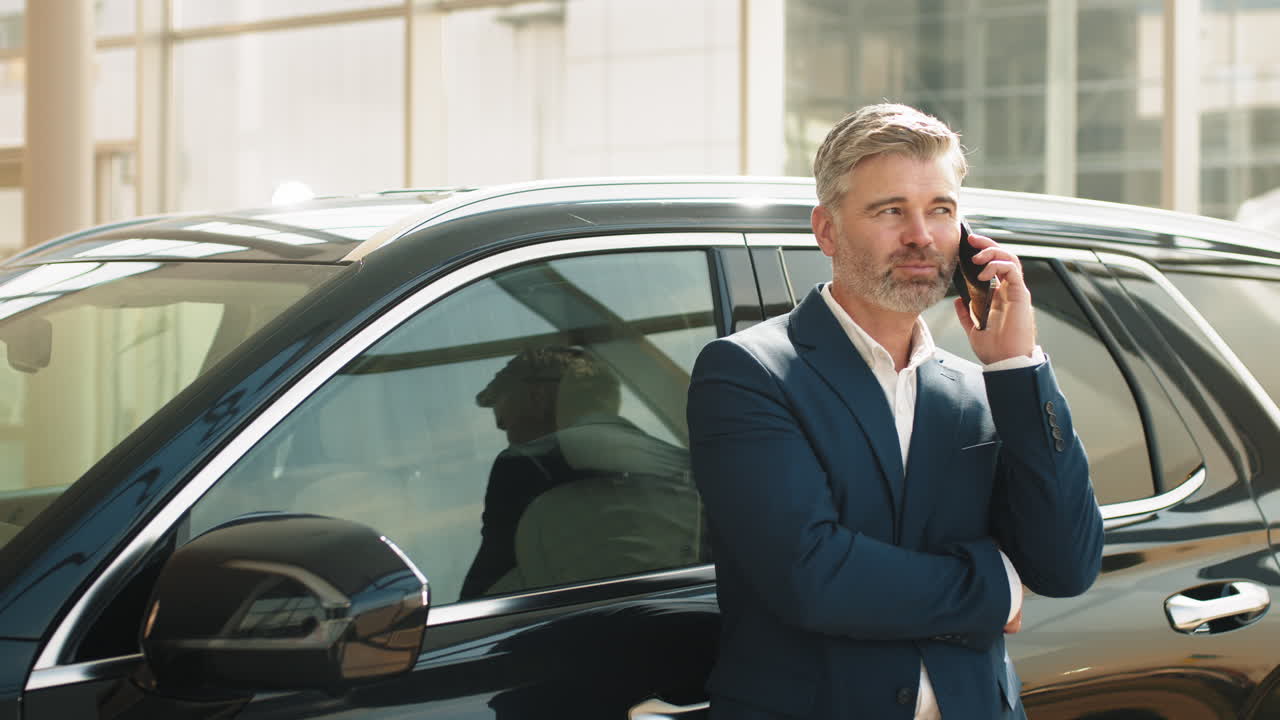 un hombre de negocios hablando por teléfono cerca de un suv negro.