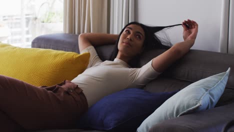 Gender-fluid-male-playing-with-hair-while-lying-on-the-couch-at-home