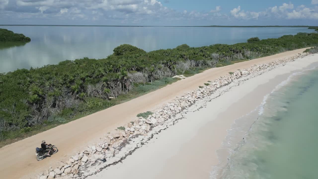 tiro aéreo de drone, motociclista sai da estrada na praia do caribe tulum méxico na reserva da biosfera